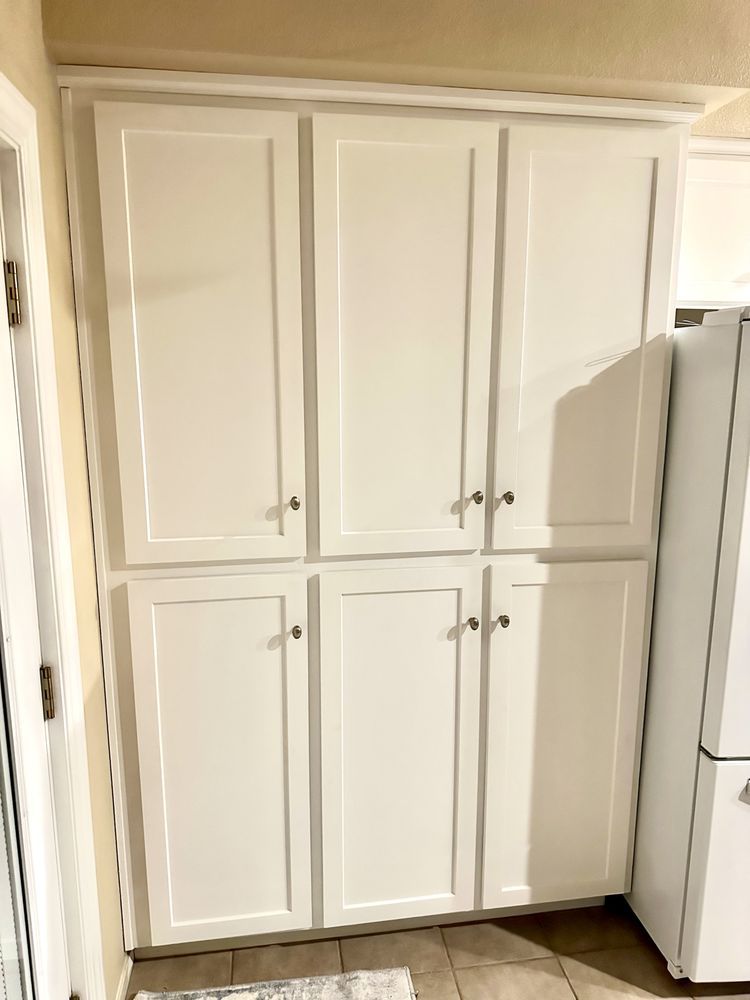 A kitchen with white cabinets and a refrigerator.