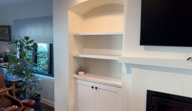 A living room with a fireplace , bookshelf , chair and television.