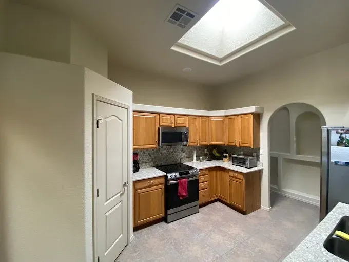 Kitchen with wooden cabinets, stainless steel appliances, and a skylight.