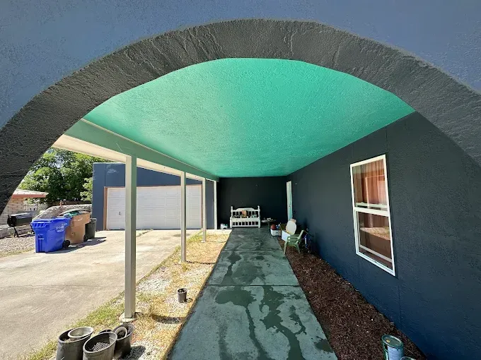 Dark archway over a teal-ceilinged walkway. A garage and house wall are seen on either side.