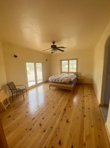 Bedroom with wood floors, bed, chair, and sliding glass doors.