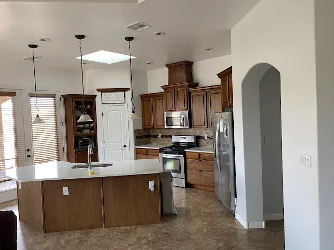 Spacious kitchen with island and dark wood cabinets, stainless steel appliances, and a skylight.