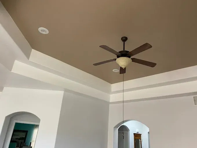 Brown and white painted ceiling with a ceiling fan and recessed lighting, in a home.