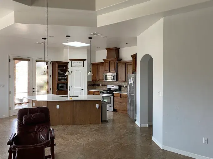 Spacious kitchen with brown cabinets, island, and a recliner in foreground.