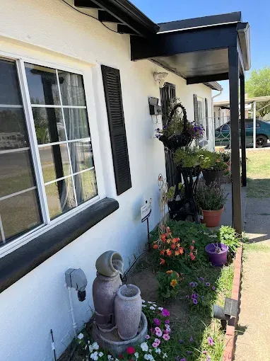 White house exterior with flowerbed, porch, and fountain.