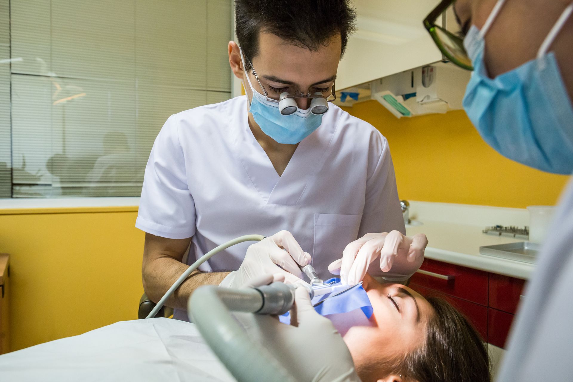 Two dental surgeons providing an operation on a patient’s mouth in a clinic.