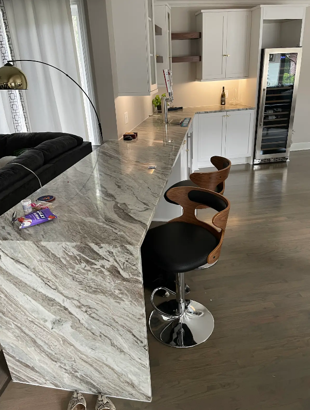 A kitchen with a marble counter top and two bar stools.