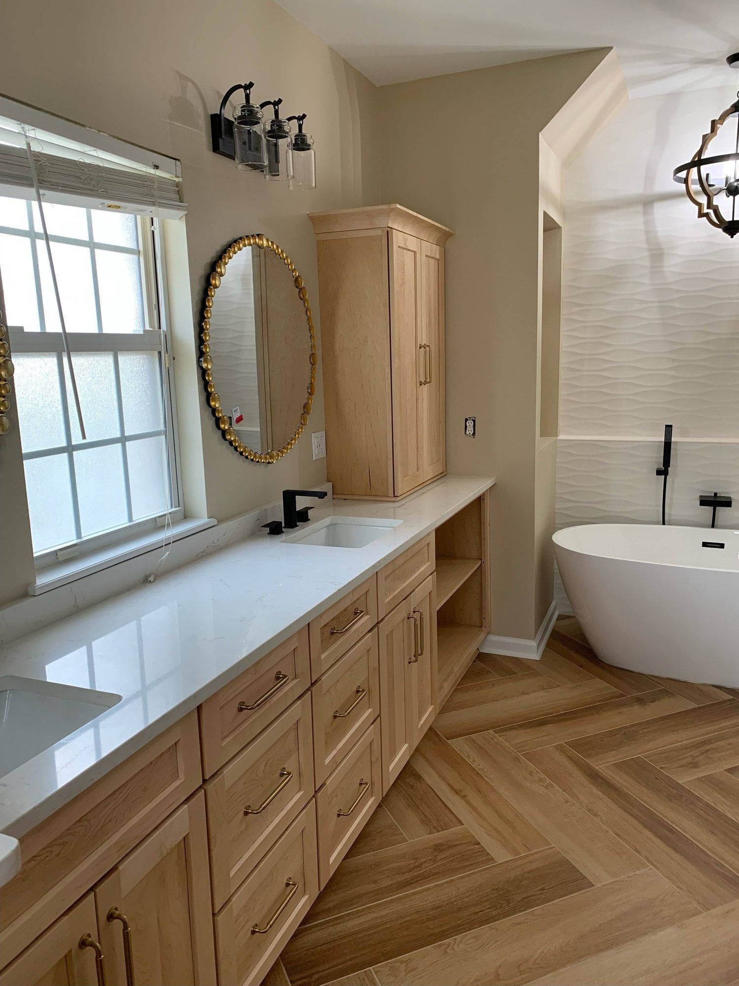 A bathroom with a tub , sink , mirror and cabinets.