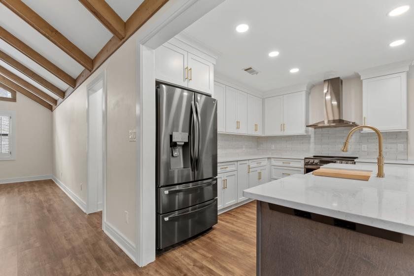 A kitchen with white cabinets and a stainless steel refrigerator.