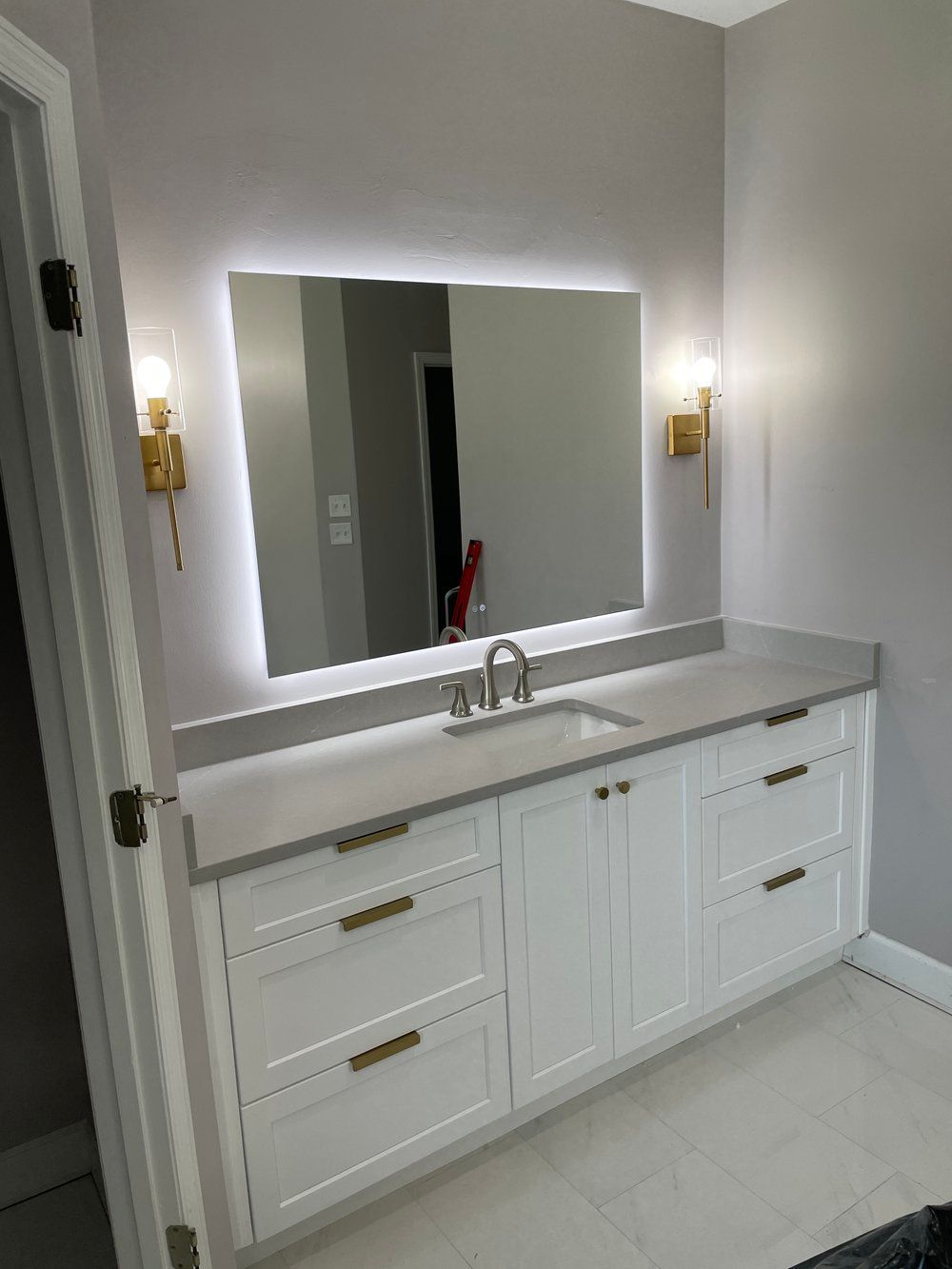 A bathroom with a sink , mirror and cabinets.