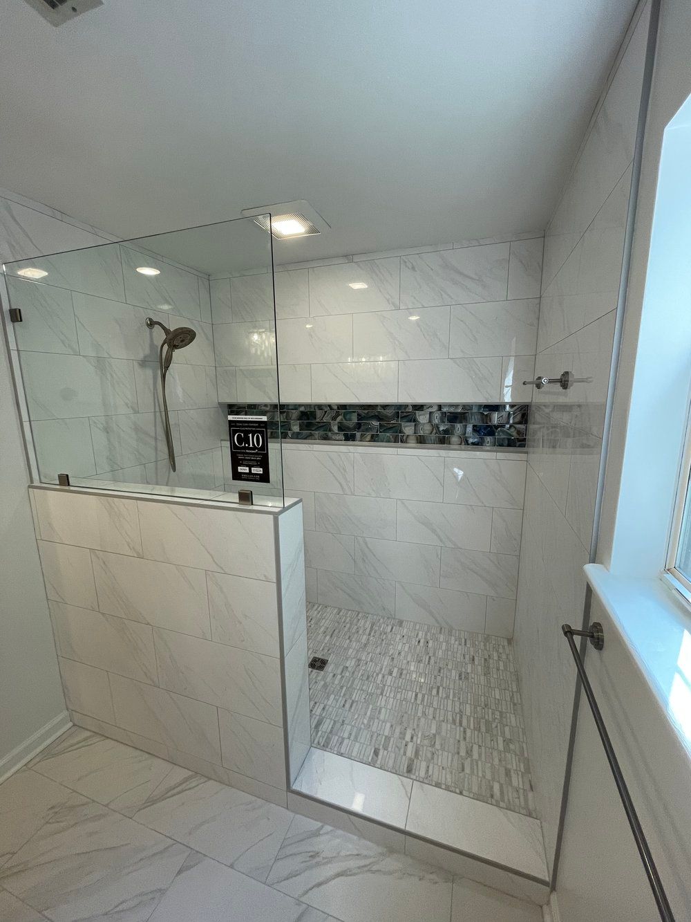 A bathroom with a walk in shower and a window.