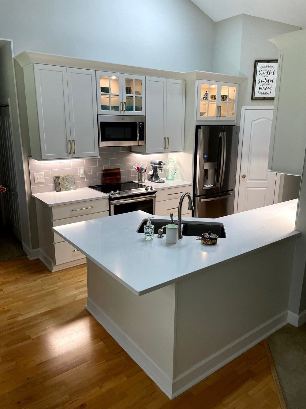 A kitchen with white cabinets , stainless steel appliances , a sink , and a large island.