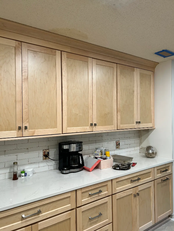 A kitchen with wooden cabinets and white counter tops