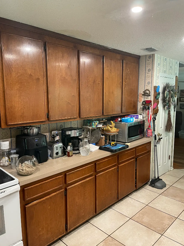 A kitchen with wooden cabinets , a stove , and a microwave.