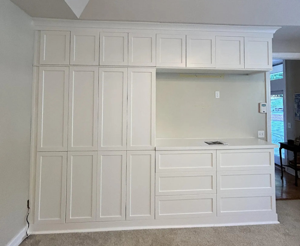 A room with a lot of white cabinets and drawers