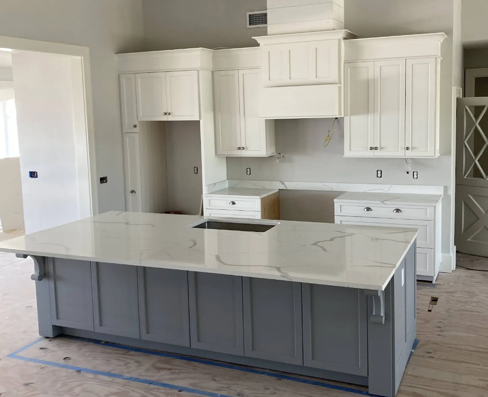 A kitchen with white cabinets and a large island in the middle