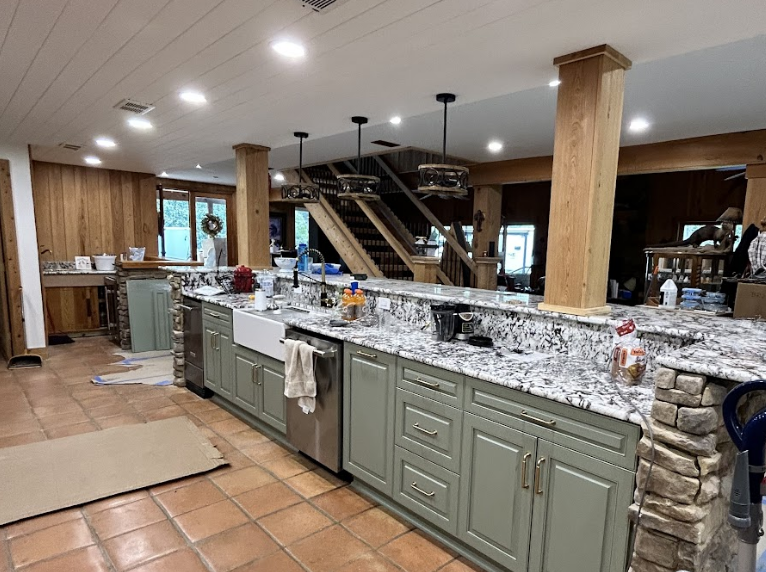 A large kitchen with green cabinets and granite counter tops.
