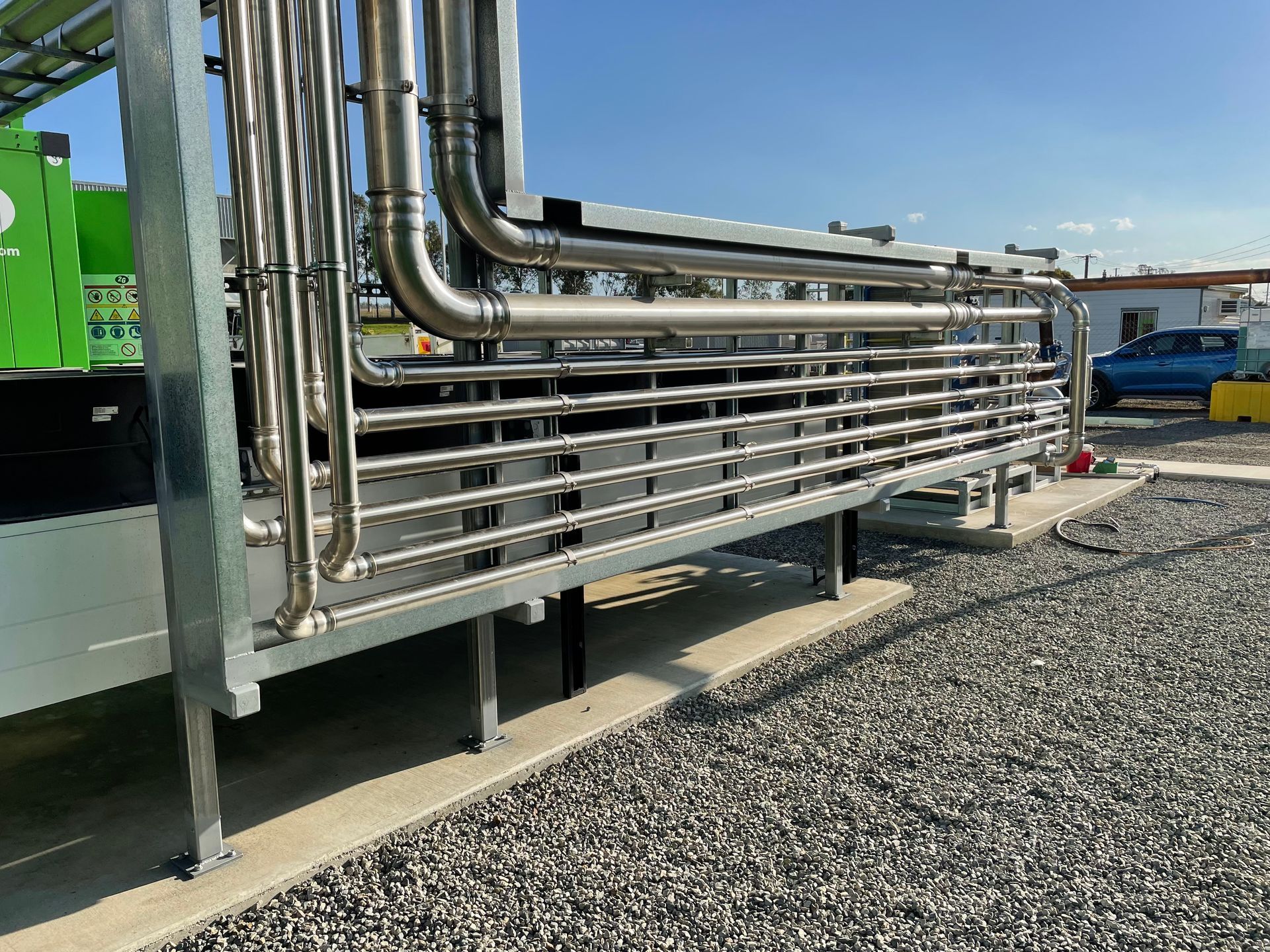 Stainless steel pipes in an industrial setting, likely for a chemical or processing plant.