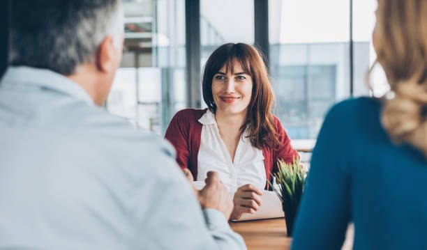 Business consultant meeting with clients at modern office desk during professional discussion.