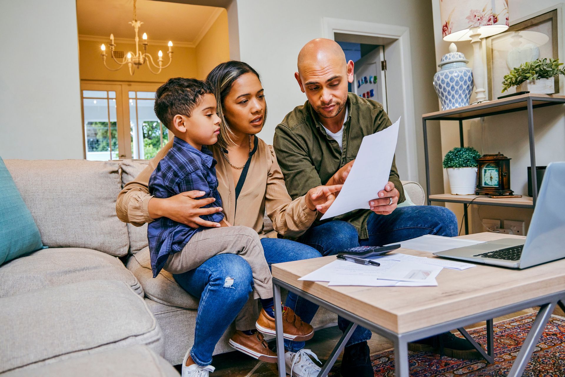 A family is sitting on a couch looking at a piece of paper.