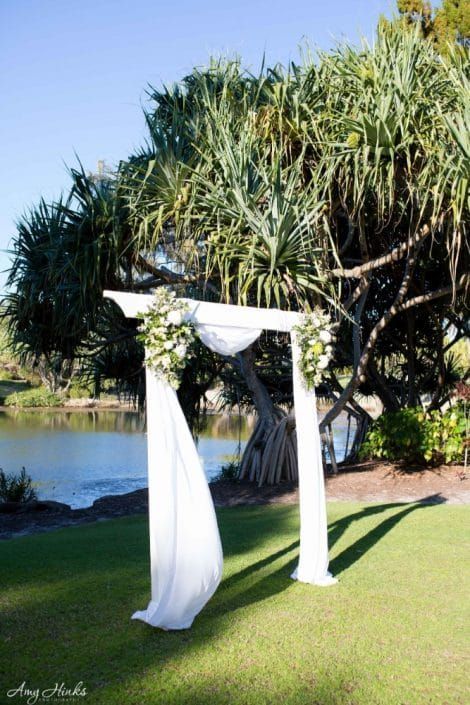 A White Arch is Sitting on Top of a Lush Green Field Next to a Body of Water — Suncoast Flowers in Birtinya, QLD