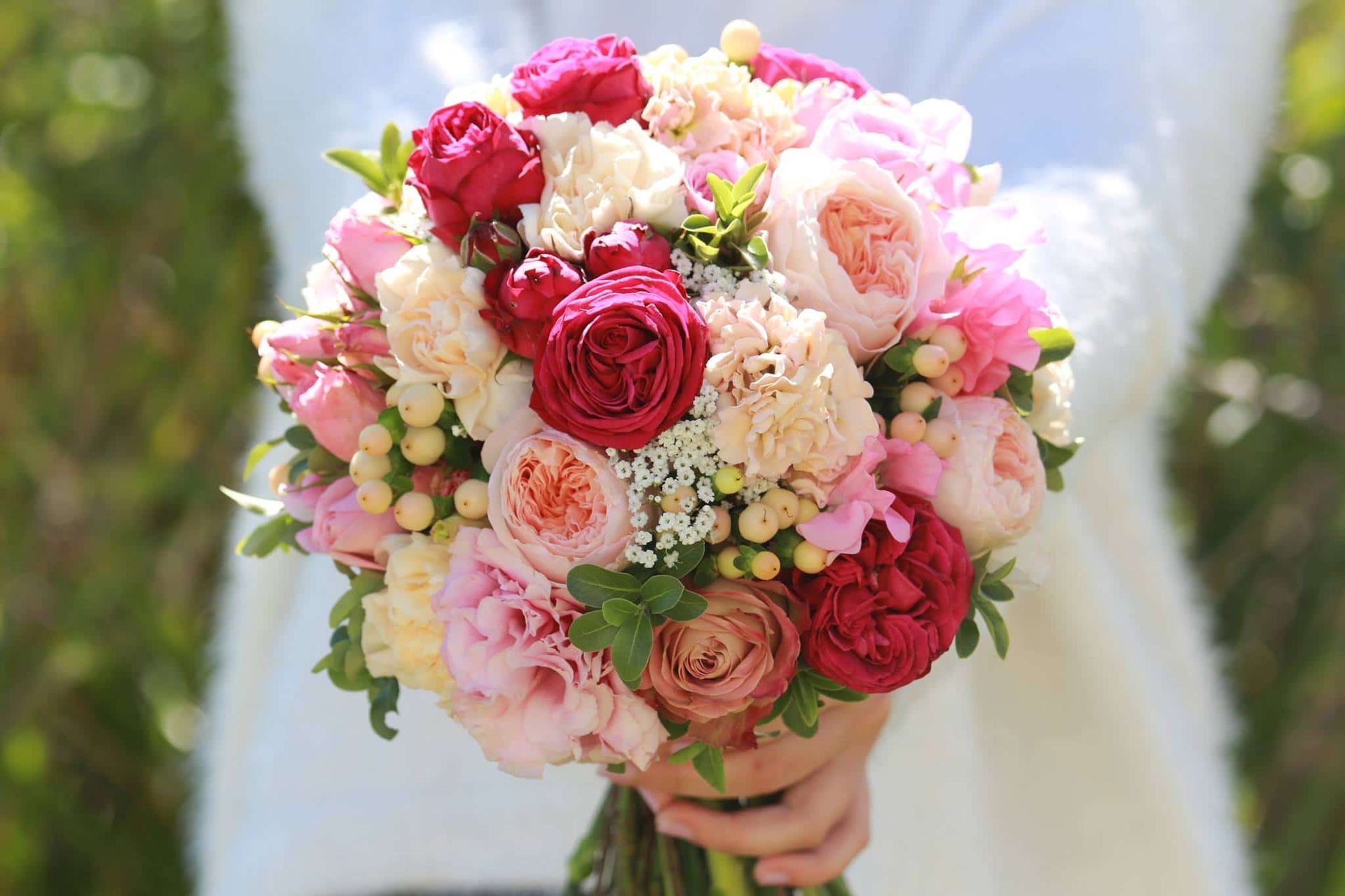 A Bride is Holding a Bouquet of Pink and Red Flowers — Suncoast Flowers in Birtinya, QLD