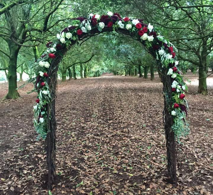 A Wooden Arch Decorated With Red and White Flowers in a Forest — Suncoast Flowers in Birtinya, QLD