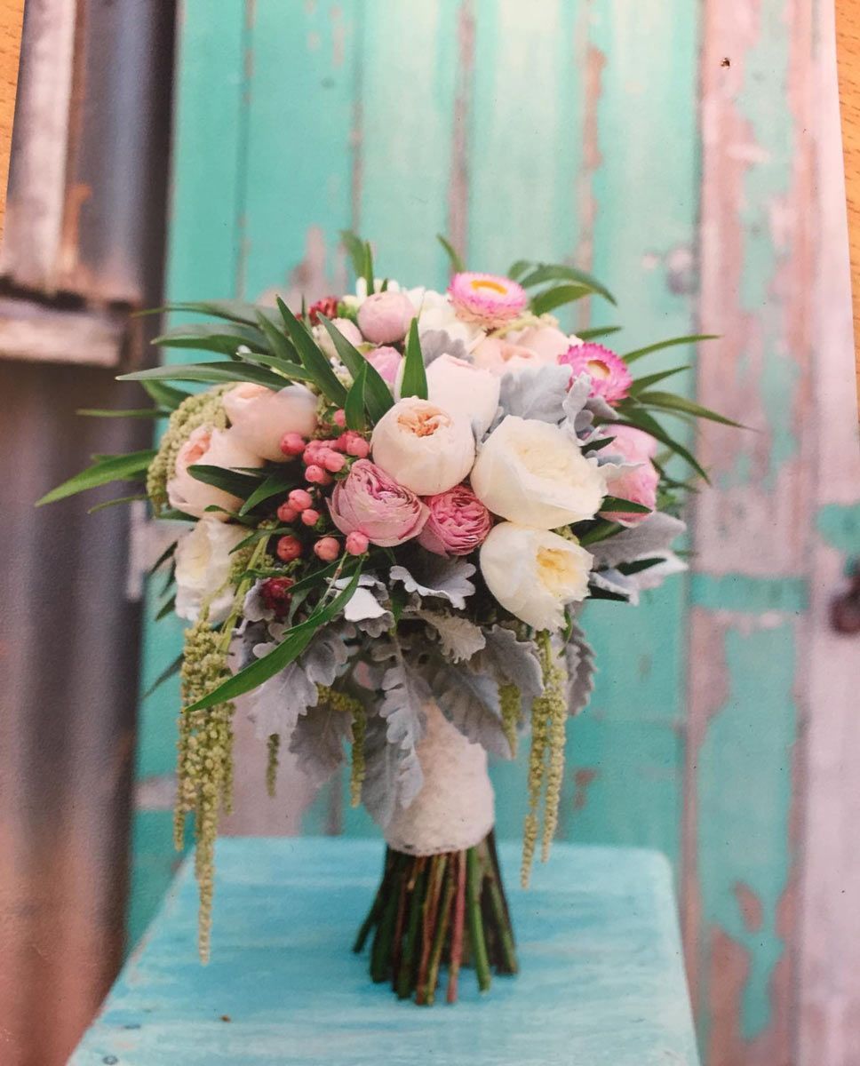 A Bouquet of Flowers is Sitting on a Table in Front of a Green Door — Suncoast Flowers in Birtinya, QLD