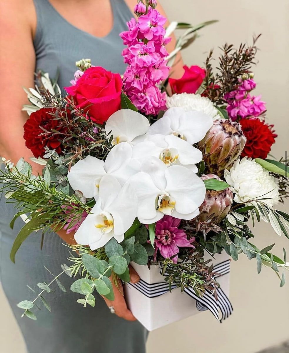 A Woman is Holding a White Box Filled With Flowers — Suncoast Flowers in Maroochydore, QLD