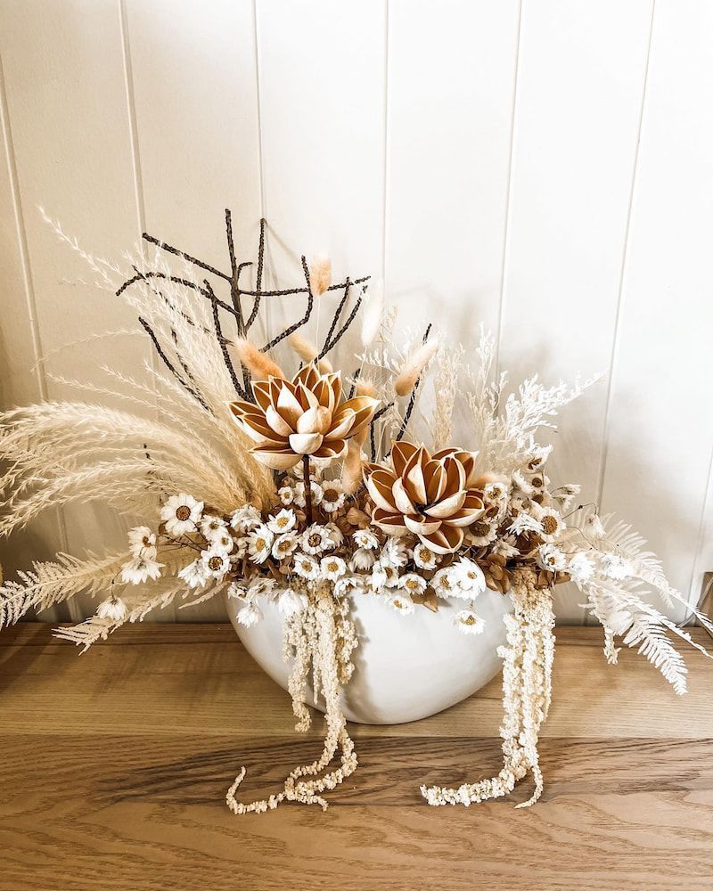 A Vase Filled With Dried Flowers is Sitting on a Wooden Table — Suncoast Flowers in Birtinya, QLD