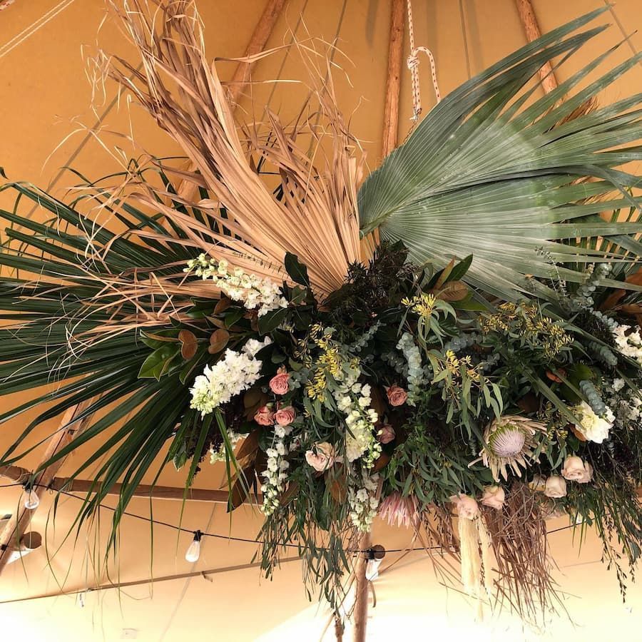 A Large Arrangement of Flowers and Leaves is Hanging From the Ceiling of a Tent — Suncoast Flowers in Caloundra, QLD