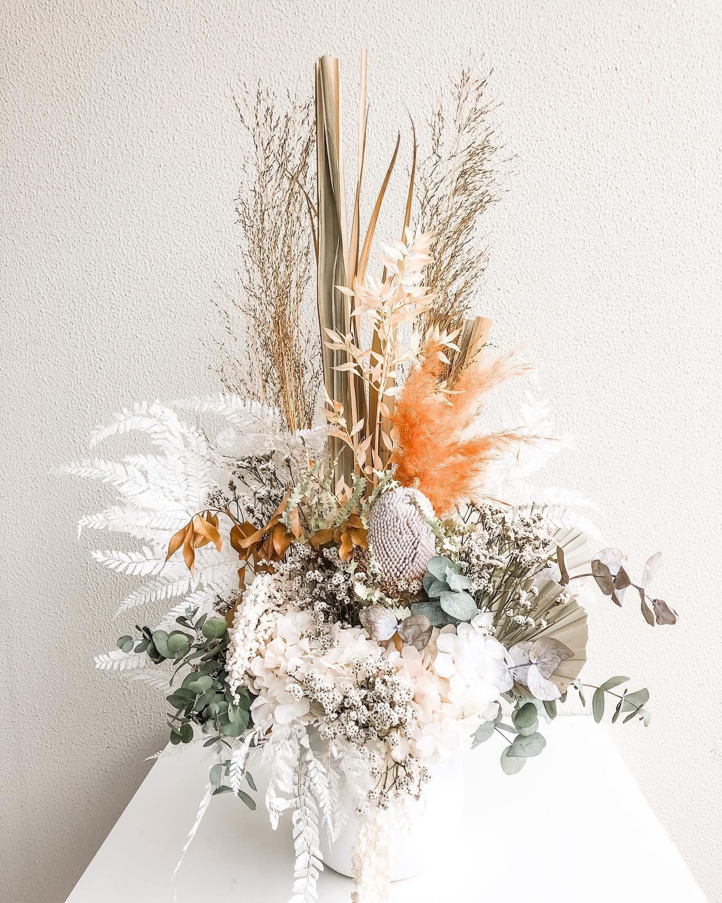 A Vase Filled With Dried Flowers is Sitting on a White Table — Suncoast Flowers in Birtinya, QLD