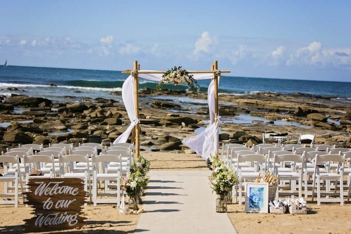 A Wedding Ceremony on the Beach With a Welcome to Our Wedding Sign — Suncoast Flowers in Birtinya, QLD