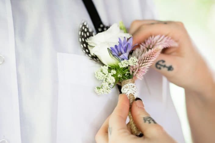 A Person With a Tattoo on Their Finger is Putting Flowers on a Man's Shirt — Suncoast Flowers in Birtinya, QLD