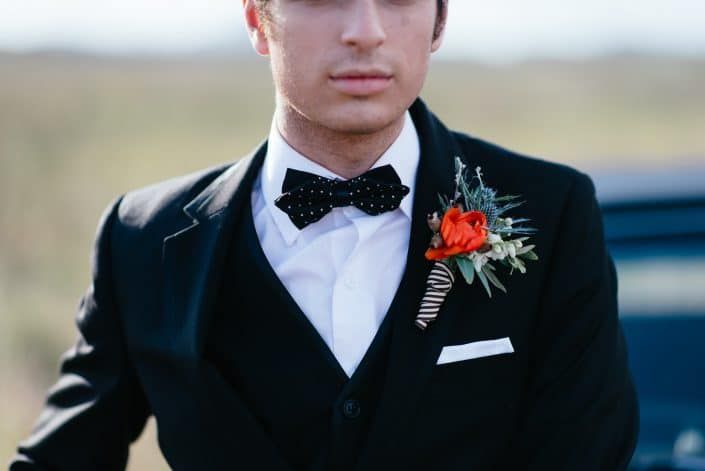 A Man in a Suit and Bow Tie is Standing in Front of a Car — Suncoast Flowers in Birtinya, QLD