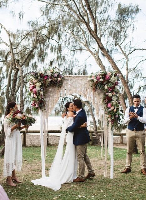 A Bride and Groom Kissing at Their Wedding Under a Floral Arch — Suncoast Flowers in Birtinya, QLD