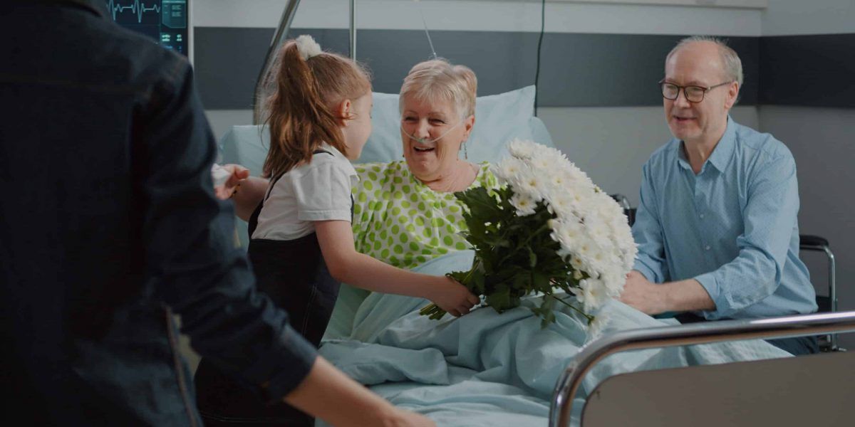 A Little Girl is Giving Flowers to an Elderly Woman in a Hospital Bed — Suncoast Flowers in Birtinya, QLD