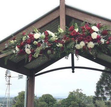 A Wooden Archway With Red and White Flowers Hanging From It — Suncoast Flowers in Birtinya, QLD