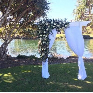 A White Arch Decorated With Flowers is Sitting on Top of a Lush Green Field — Suncoast Flowers in Birtinya, QLD