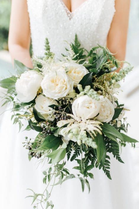 A Bride in a White Dress is Holding a Bouquet of White Flowers and Greenery — Suncoast Flowers in Birtinya, QLD