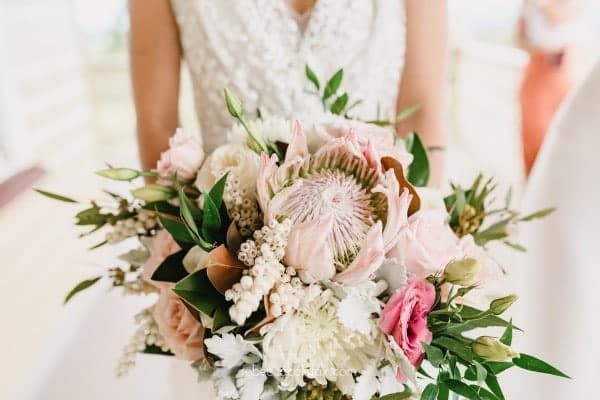 A Bride in a White Dress is Holding a Bouquet of Flowers — Suncoast Flowers in Birtinya, QLD