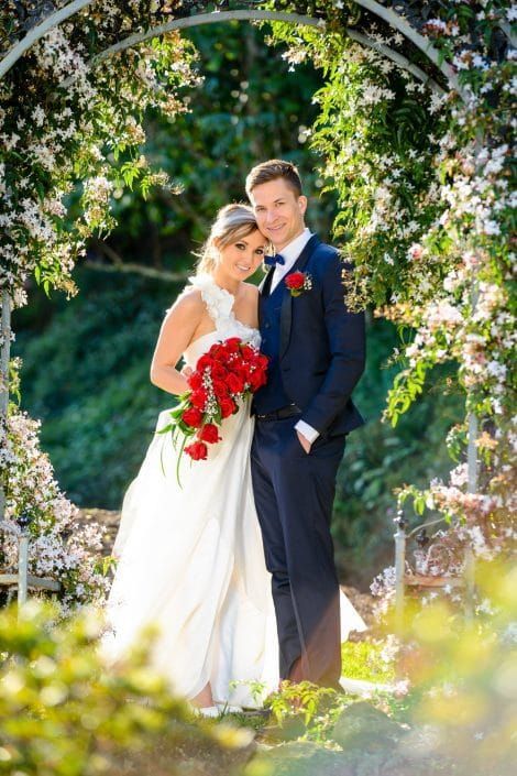 A Bride and Groom Are Posing for a Picture Under an Archway — Suncoast Flowers in Birtinya, QLD