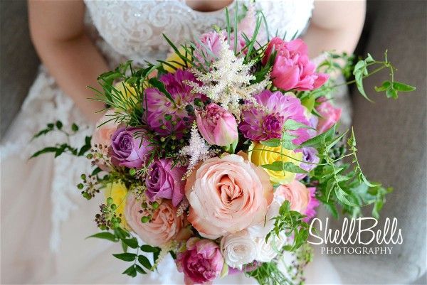 A Bride is Holding a Bouquet of Pink and Yellow Flowers — Suncoast Flowers in Birtinya, QLD