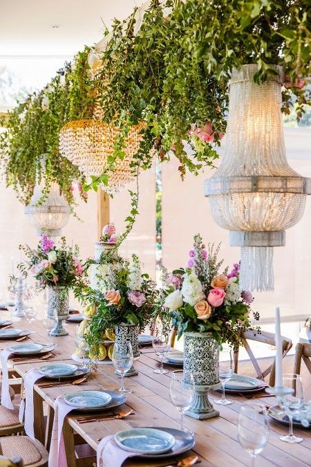 A Table With Plates, Glasses, Vases of Flowers and Chandeliers Hanging From the Ceiling — Suncoast Flowers in Birtinya, QLD