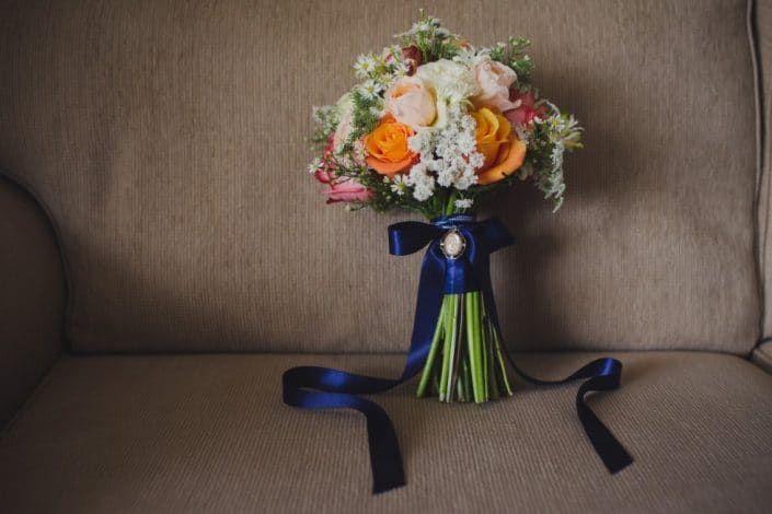 A Bouquet of Flowers is Sitting on a Couch With a Blue Ribbon — Suncoast Flowers in Birtinya, QLD