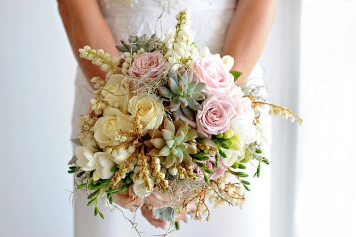 A Bride is Holding a Bouquet of Flowers in Her Hands — Suncoast Flowers in Birtinya, QLD