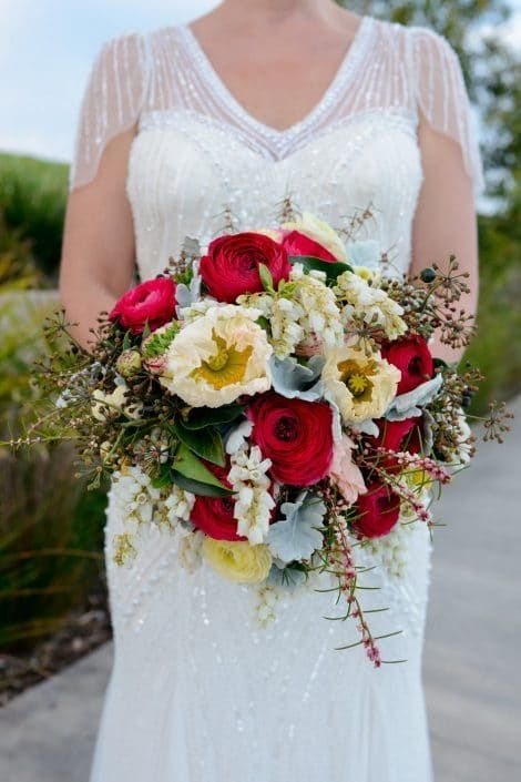 A Bride in a White Dress is Holding a Bouquet of Red and White Flowers — Suncoast Flowers in Birtinya, QLD