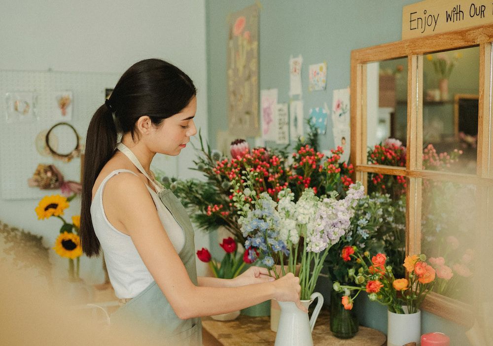 A Woman is Arranging Flowers in a Vase in a Flower Shop — Suncoast Flowers in Caloundra, QLD