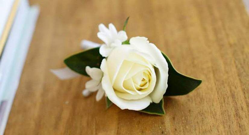 A White Rose With Green Leaves is Sitting on a Wooden Table — Suncoast Flowers in Birtinya, QLD