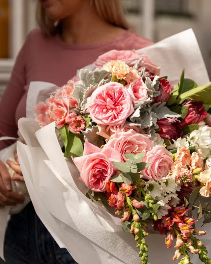 A Woman in an Apron is Holding a Bouquet of Flowers — Suncoast Flowers in Birtinya, QLD